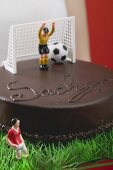 Frau hält Sachertorte mit Fussballdeko