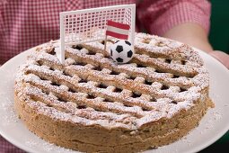 Frau hält Linzertorte mit Fussballdeko und Österreich-Flagge