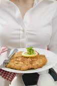 Woman holding plate of Wiener schnitzel (veal escalope) on football