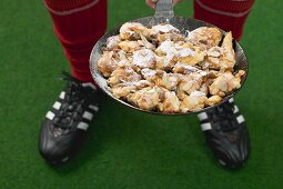 Fussballspieler hält Pfanne mit Kaiserschmarren