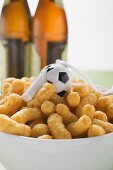 Peanut puffs with whistle in bowl in front of bottles of beer