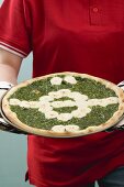 Fussballspielerin hält Spinatpizza mit Mozzarella
