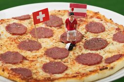 Salami pizza with toy footballer and two flags