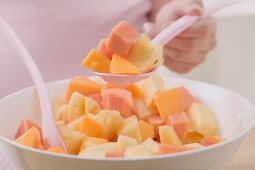 Woman taking spoonful of fruit salad out of bowl