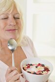 Woman enjoying yoghurt with berries and flaked almonds