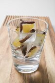 Ice cubes with spices and pieces of fruit in glass