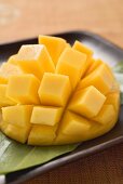 Diced mango still attached to the skin on brown plate