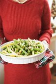 Woman holding dish of beans with flaked almonds (Christmas)