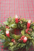 Advent wreath with four burning candles on checked cloth