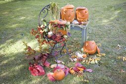 Herbstliche Gartendeko mit Kürbissen, Blumen und Laub