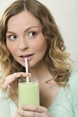 Woman drinking cucumber shake through a straw