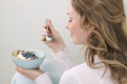 Frau isst Müsli mit Heidelbeeren