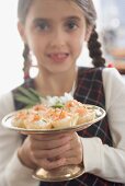 Girl holding salmon tarts on silver stand