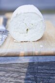 Goat's cheese roll on chopping board