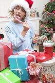 Junge mit Weihnachtsmütze isst Zuckerstange