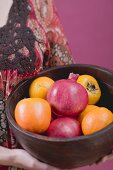 Woman holding fresh fruit in wooden bowl