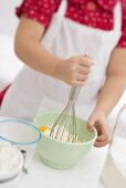 Small girl mixing egg, flour and butter with whisk