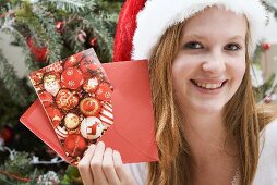 Woman in Father Christmas hat holding Christmas card & envelope