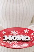 Hände halten weihnachtlichen Teller mit Buchstaben HOHO