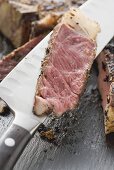 Slice of spicy rib eye steak on knife (close-up)