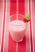 Strawberry milk in glass with fresh strawberry on rim