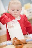 Toddler reaching into jar of flour