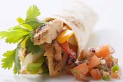 Wrap filled with chicken and pepper, salsa beside it