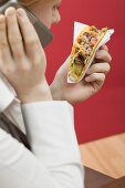 Woman on the phone with a taco in her hand