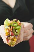 Frau hält Taco mit Gemüsefüllung