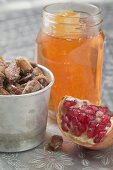 Roasted almonds, wedge of pomegranate and jar of honey