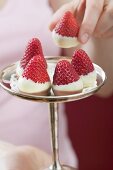 Woman taking chocolate-dipped strawberry from silver stand