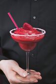 Man holding a glass of Strawberry Daiquiri