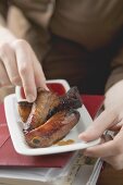 Woman eating glazed pork ribs in office