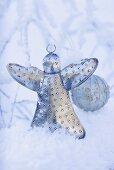 Silver angel and Christmas bauble in snow