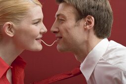Couple eating a strand of spaghetti from both ends
