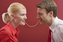 Couple eating a strand of spaghetti from both ends