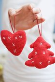 Hand holding two knitted Christmas tree ornaments