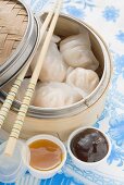 Dim Sum im Bambusdämpfer, daneben zwei Saucen (Asien)