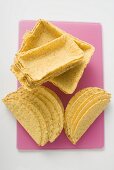 Assorted taco shells on pink chopping board