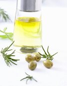 Olivenöl, grüne Oliven und Rosmarin