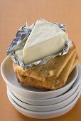 Processed cheese in foil on crackers in stacked dishes