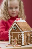Small girl behind gingerbread house