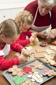 Grandmother showing granddaughters how to decorate Xmas biscuits