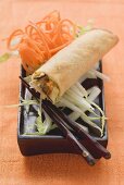 Spring roll on raw vegetables with chopsticks