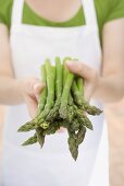 Young woman holding fresh green asparagus