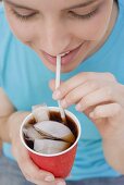 Junge Frau trinkt Cola mit Strohhalm
