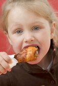 Little girl eating chicken drumstick
