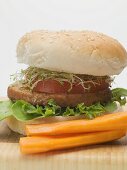 Burger with sprouts and tomato, carrots beside it