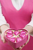 Woman holding box of heart-shaped chocolates