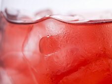 Glass of rosé wine with ice cubes (detail)